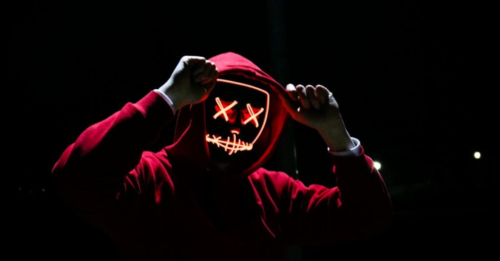 A spooky illuminated mask figure with a red hoodie in a dark setting, perfect for Halloween themes.